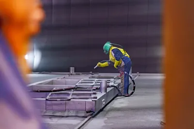 Abrasive blasting technician performing grit blasting on steel structure